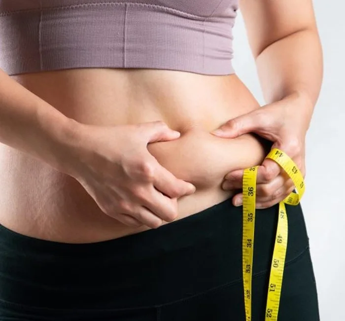 Person tracking waistline progress with a tape measure